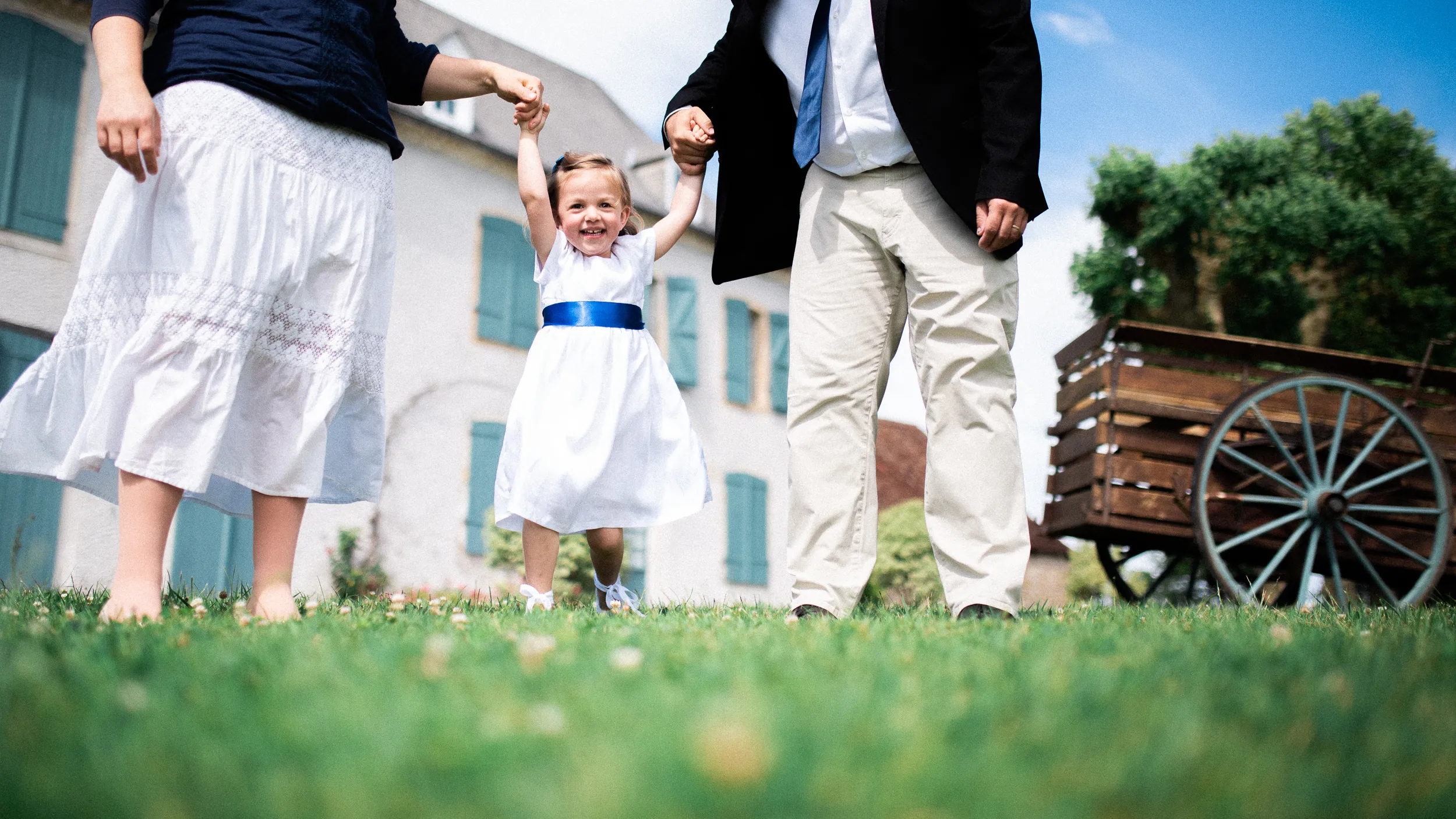 Petite fille en robe blanche portée par ses parents lors d'une séance photo en famille