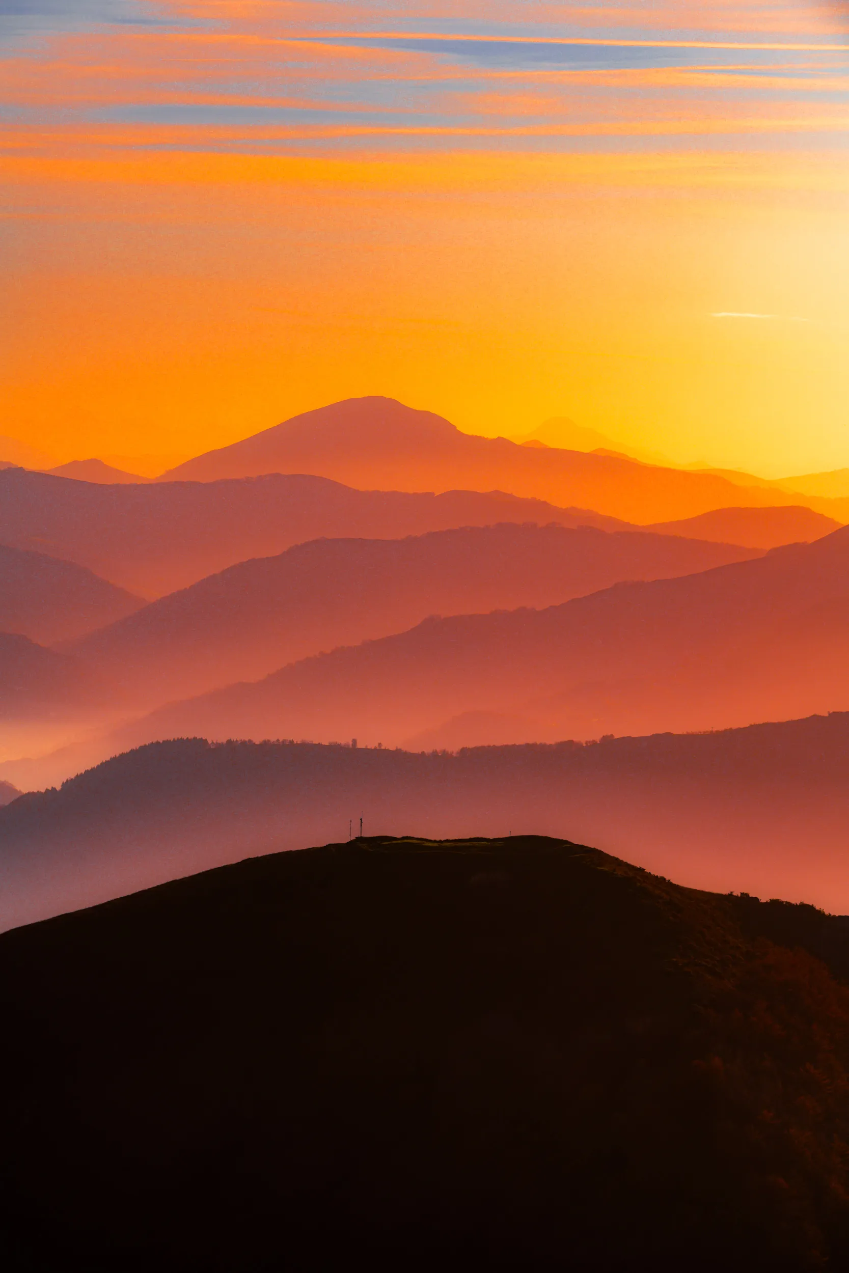 Des crêtes successives dans la brume orangée du couchant, vues depuis Aiako Harria, au Pays basque