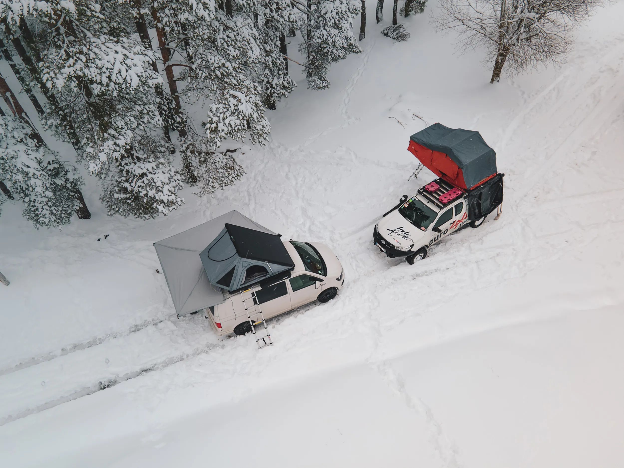 Vue aérienne au drone de deux pick-up avec tentes de toit dépliées dans la neige