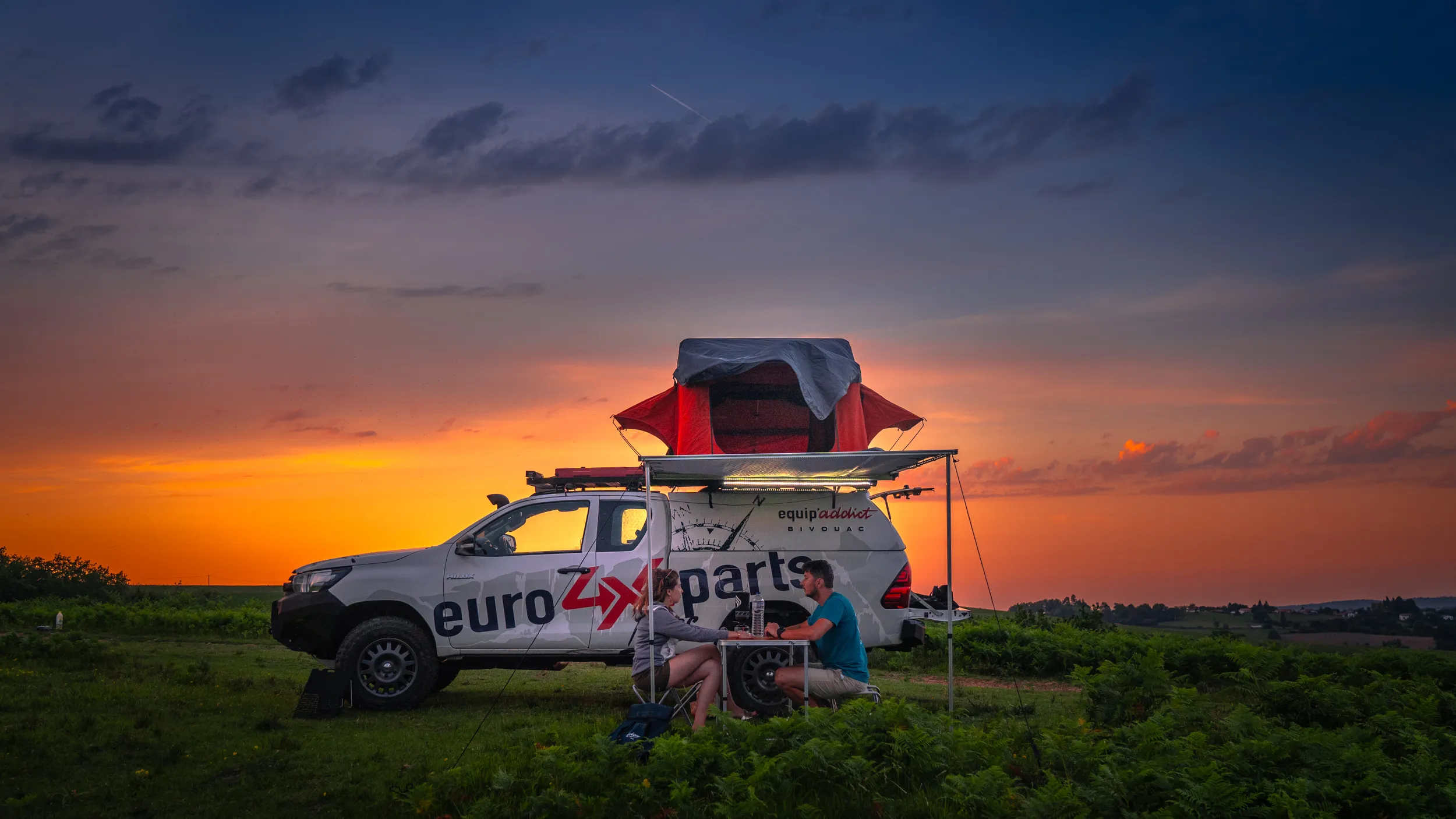 Bivouac au coucher du soleil avec un pick-up Euro4x4Parts, tente de toit et auvent Equip'Addict