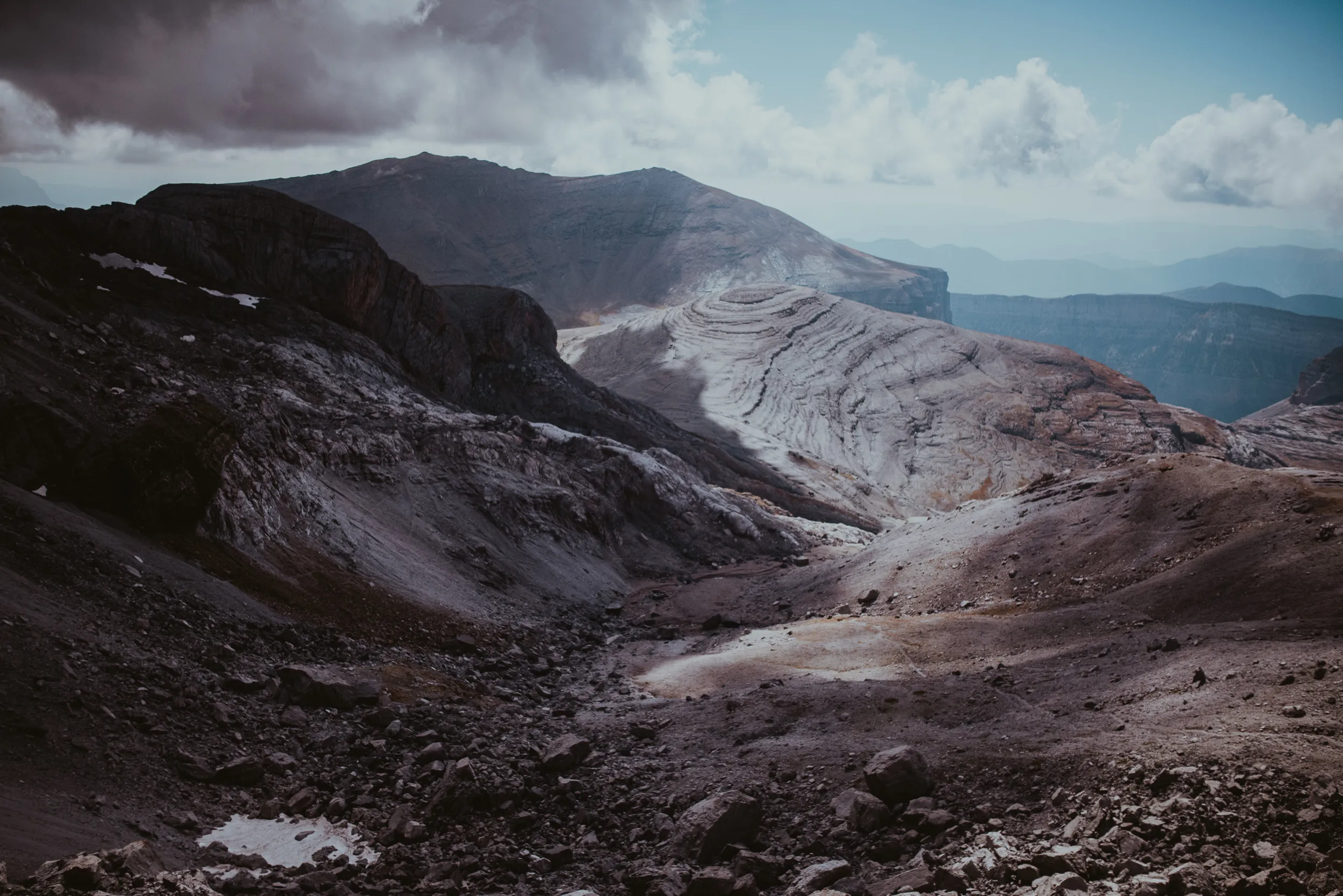 Dalles calcaires polies et pierriers sous un ciel changeant, aux abords de la brèche de Roland