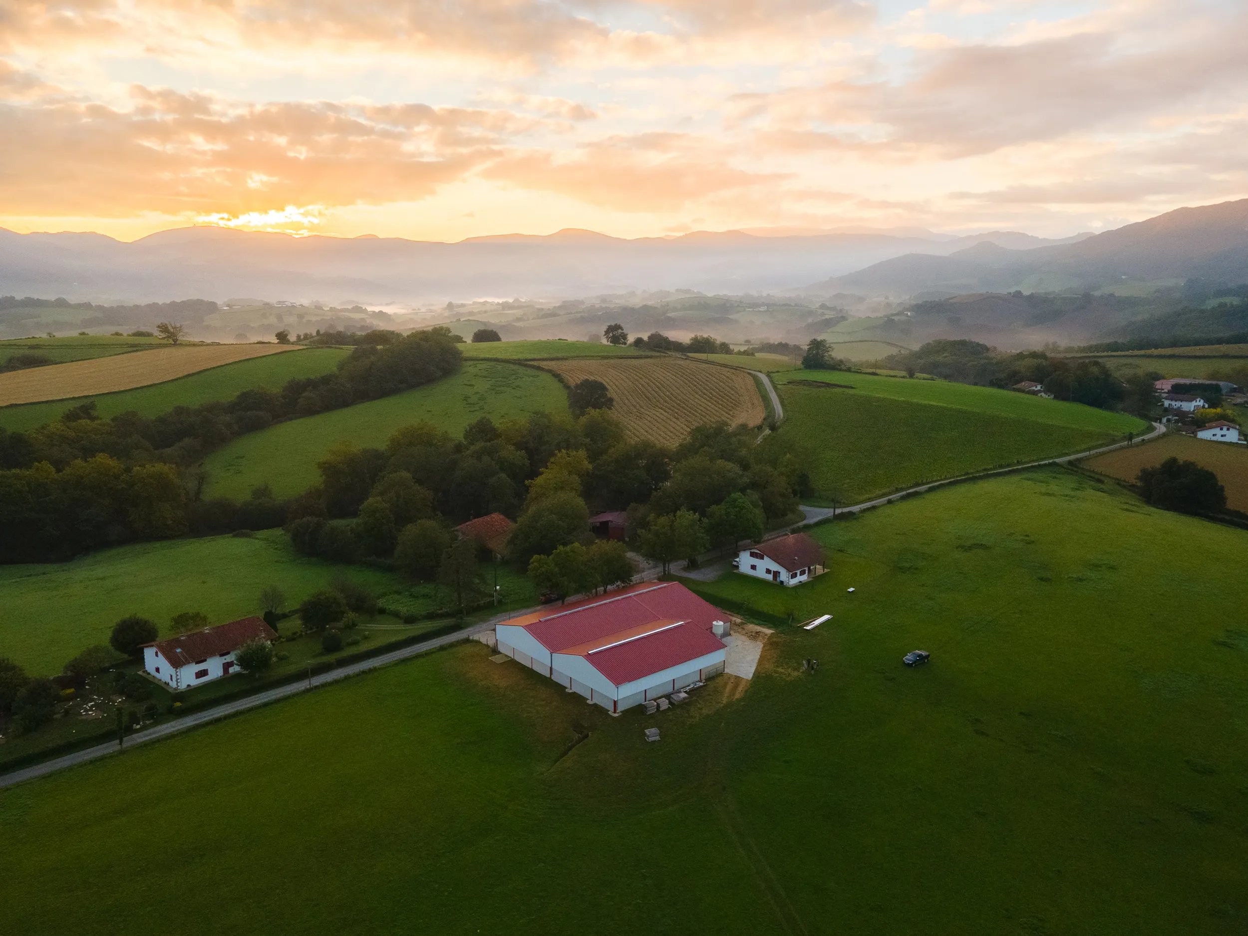 Vue aérienne au drone d'une ferme et des collines au lever du soleil