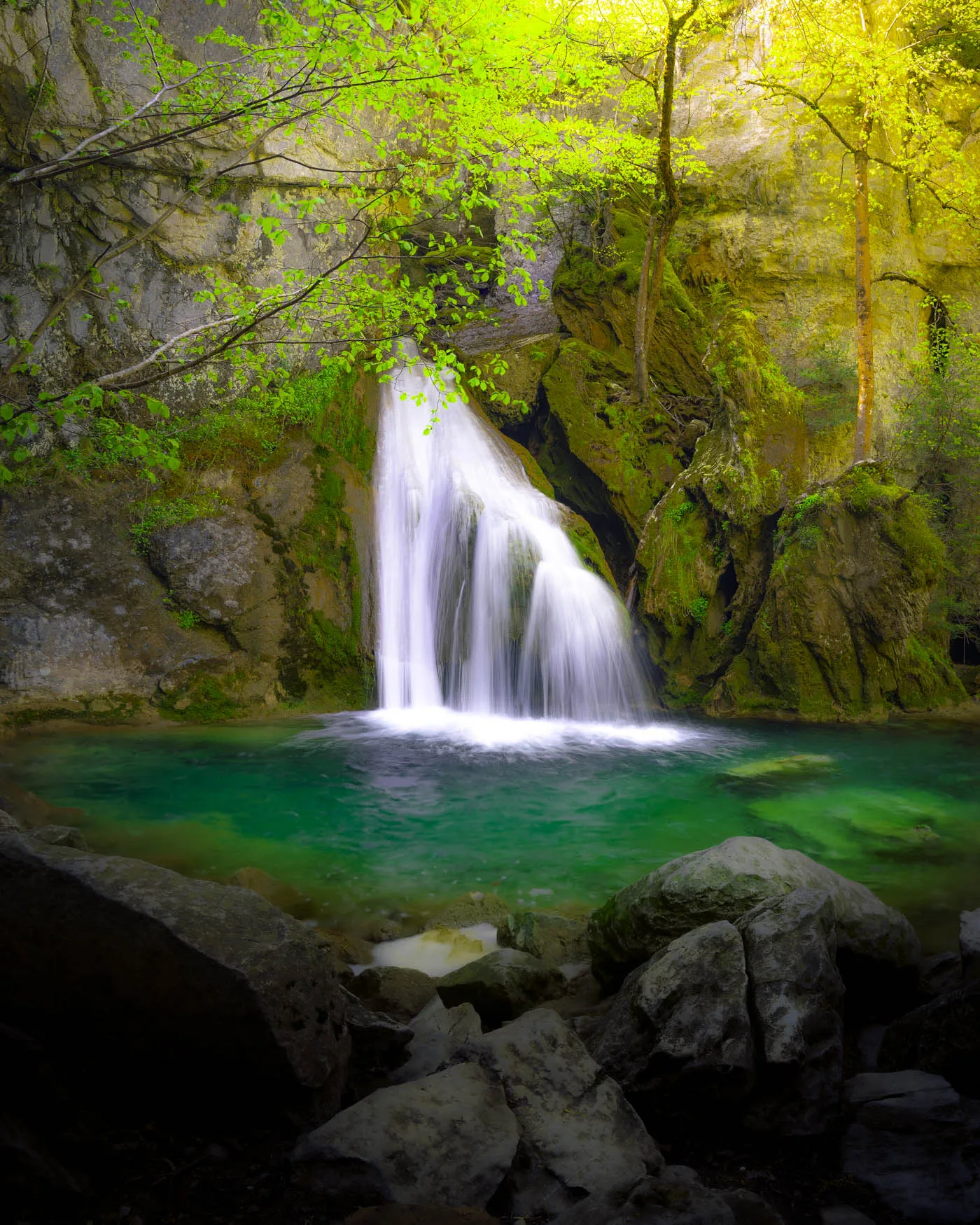 La cascade de Belabarze tombe dans une vasque émeraude, entourée de mousses et de jeunes feuilles