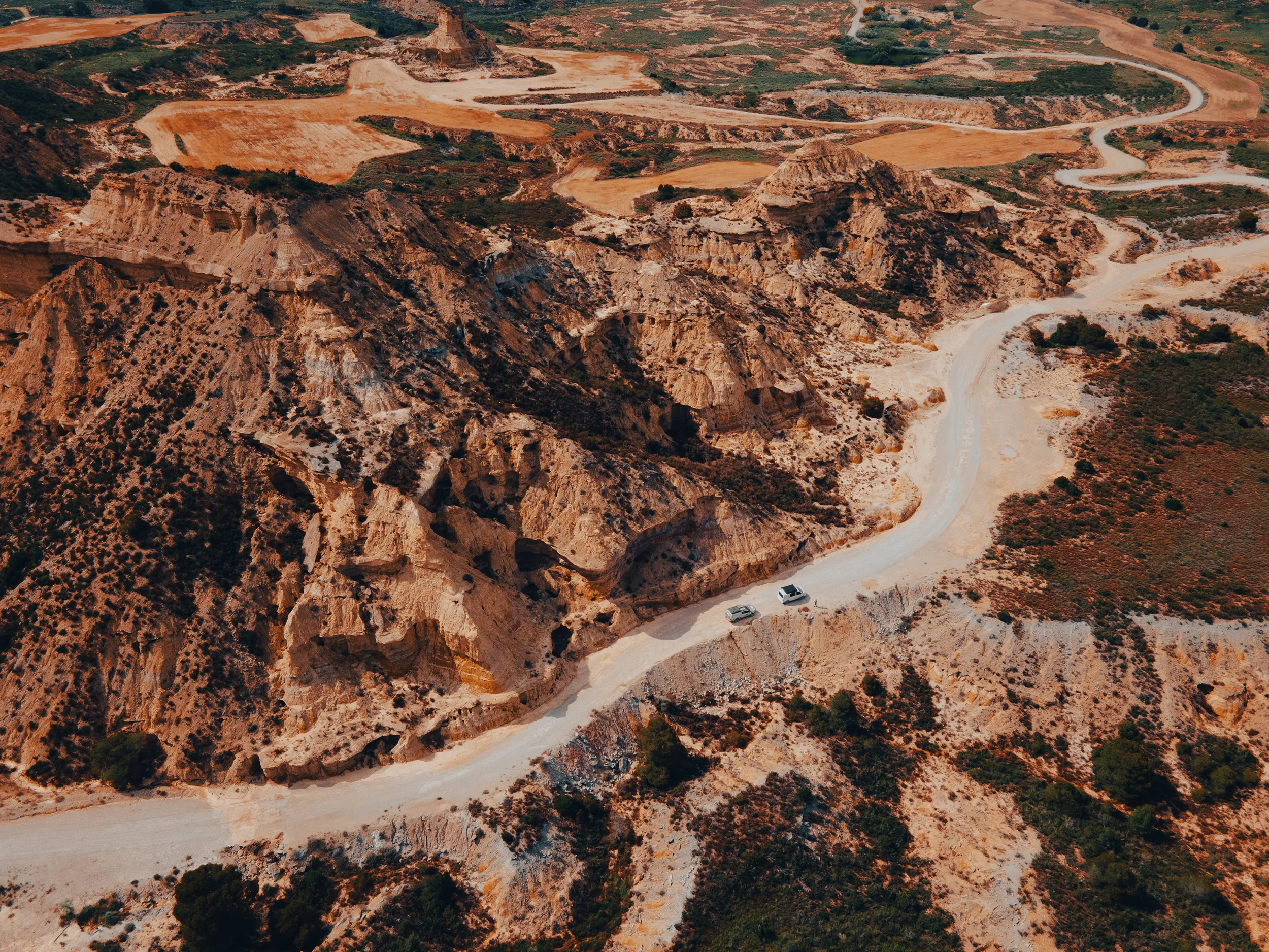 Vue aérienne au drone d'un convoi de 4x4 traversant un canyon ocre du désert des Monegros