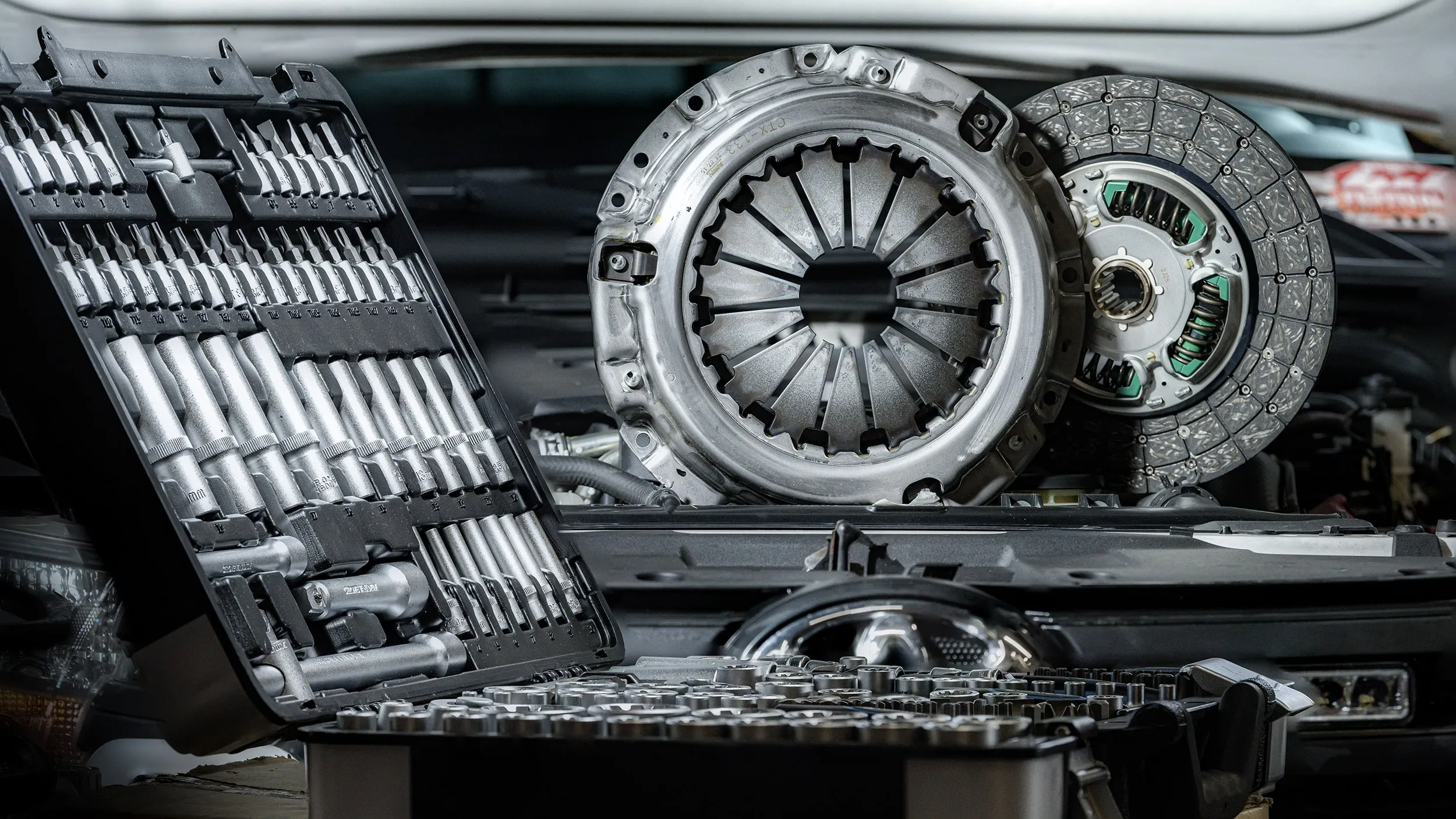 Kit d'embrayage posé sur une caisse à outils devant un 4x4, net du premier au dernier plan grâce au focus stacking
