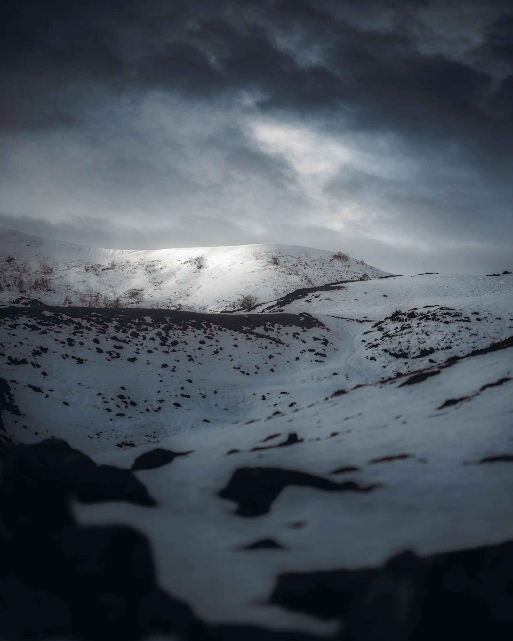 Un plateau enneigé sous un ciel tourmenté, éclairé par une trouée de lumière, à Lauriolle