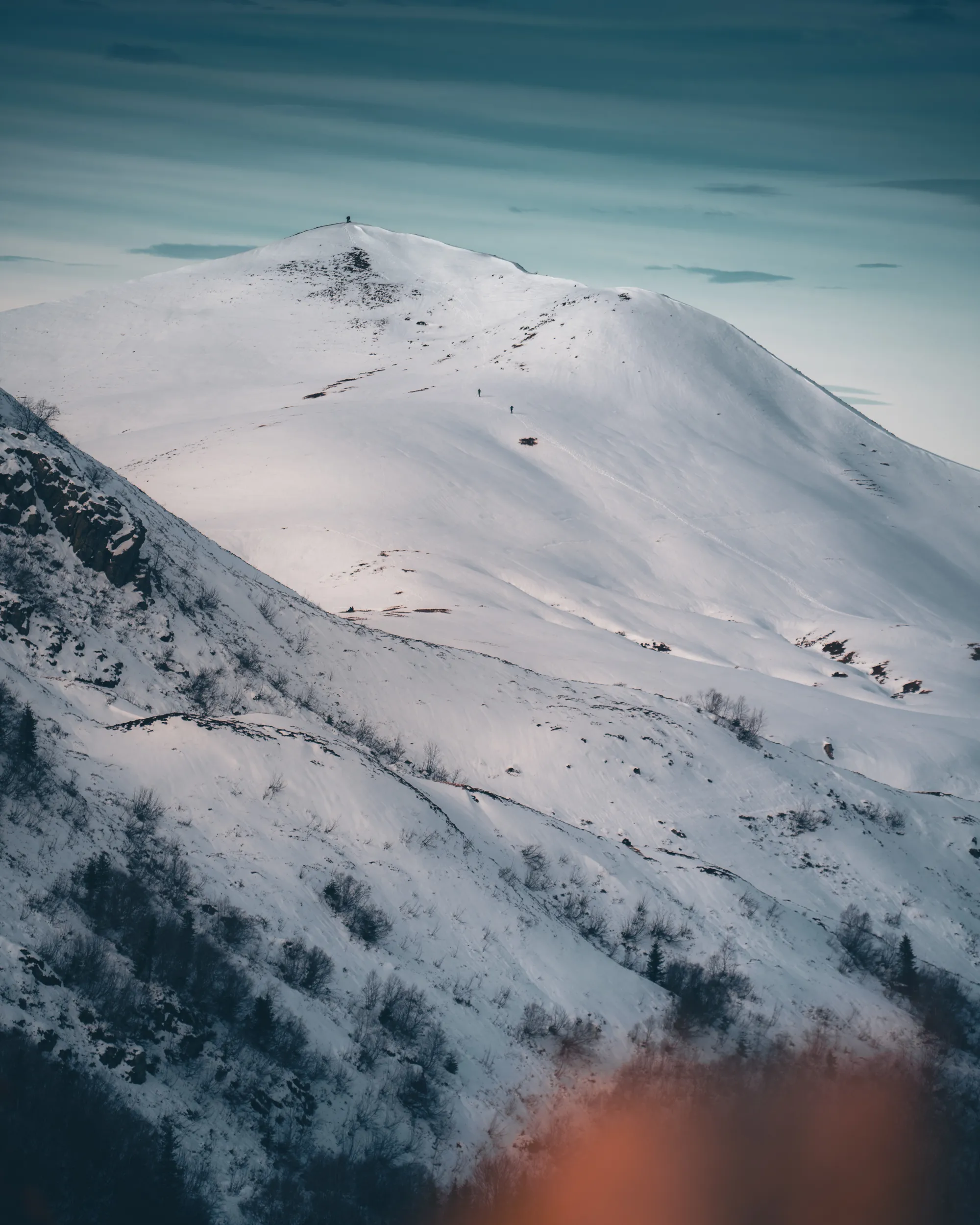 Un sommet arrondi couvert de neige, de minuscules randonneurs sur l'arête, à Lauriolle