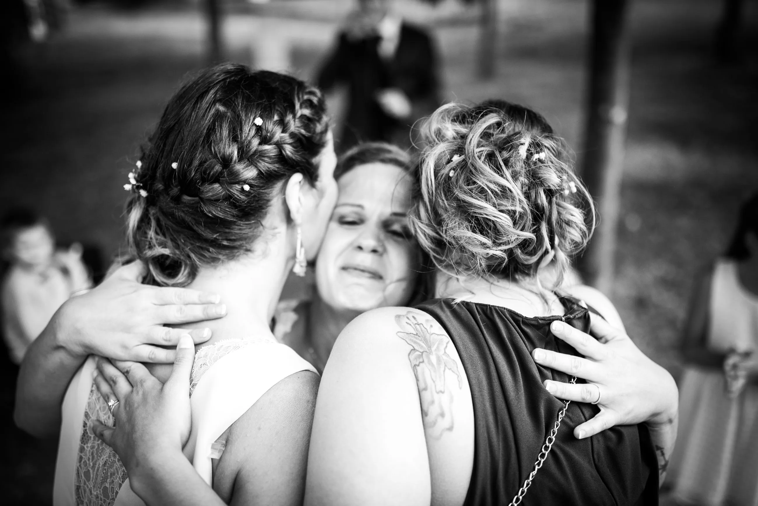 Étreinte émue entre la mariée et ses proches, en noir et blanc