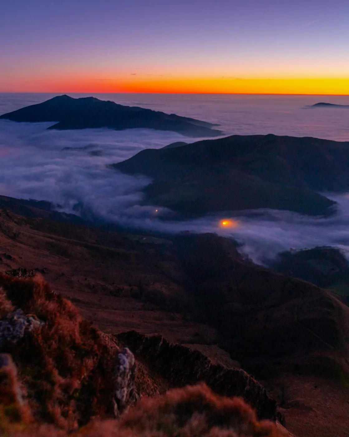 Mer de nuages au crépuscule depuis la crête d'Iparla, éclairée par les lumières d'un village