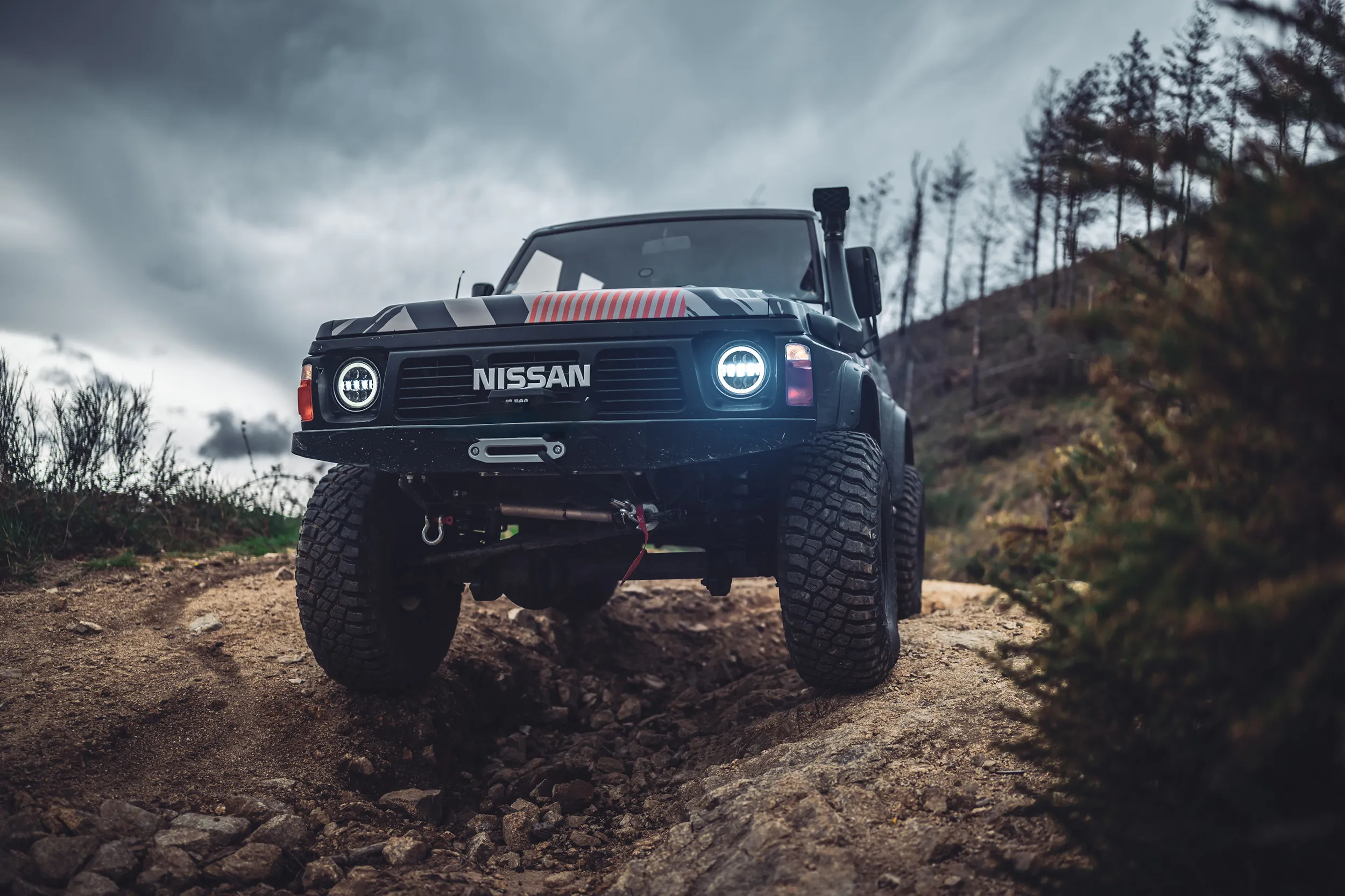 Nissan Patrol préparé, phares allumés, sous un ciel orageux