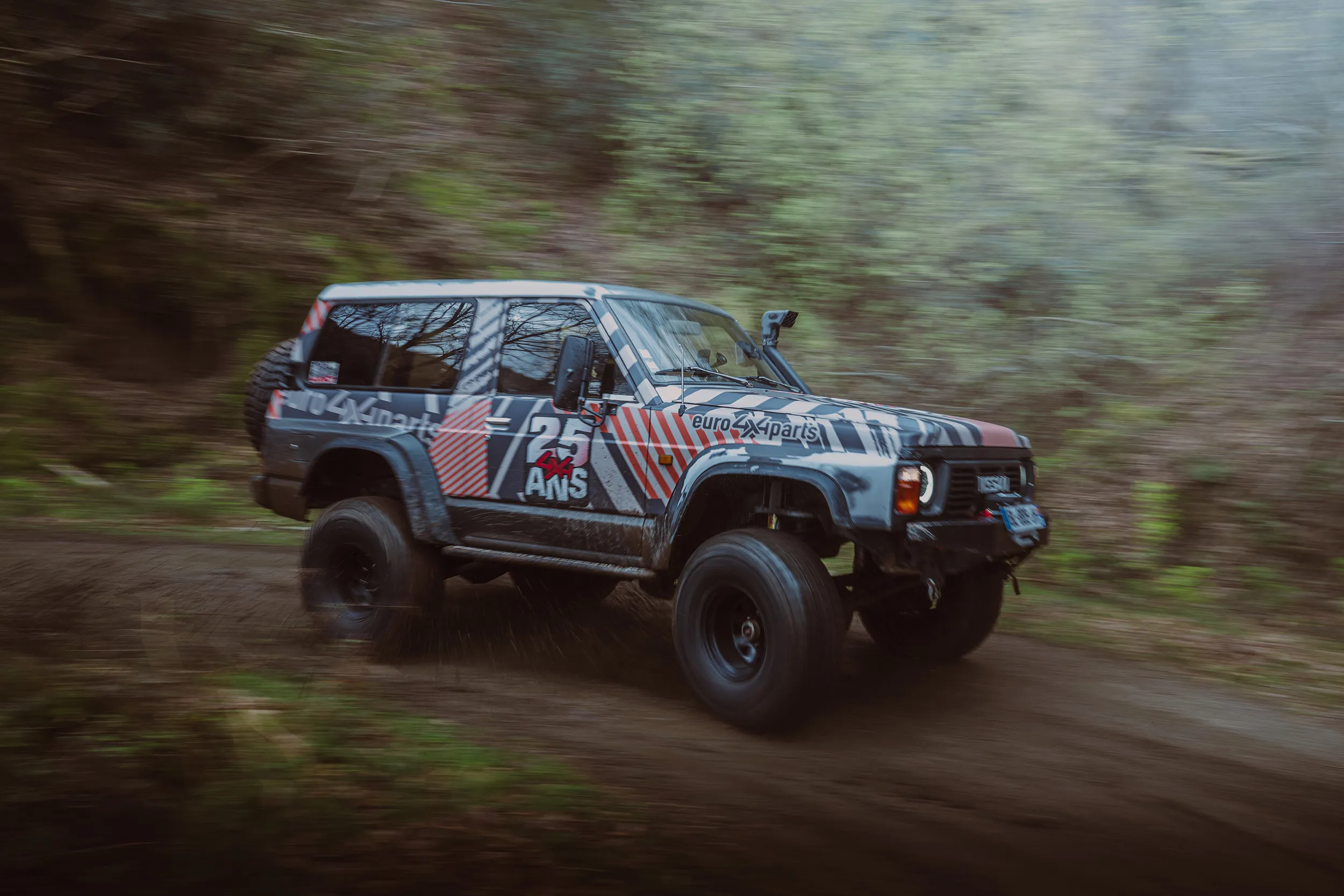 Nissan Patrol aux couleurs d'Euro4x4Parts lancé sur une piste en forêt