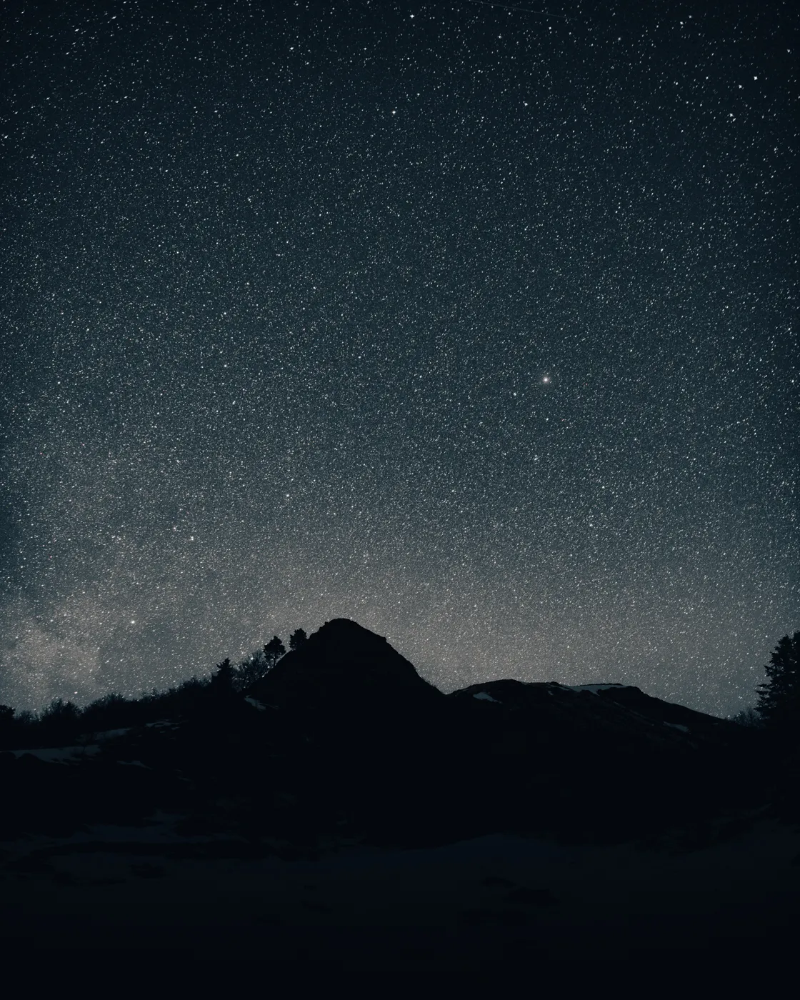 Un ciel constellé d'étoiles au-dessus de la silhouette noire d'un sommet pyrénéen