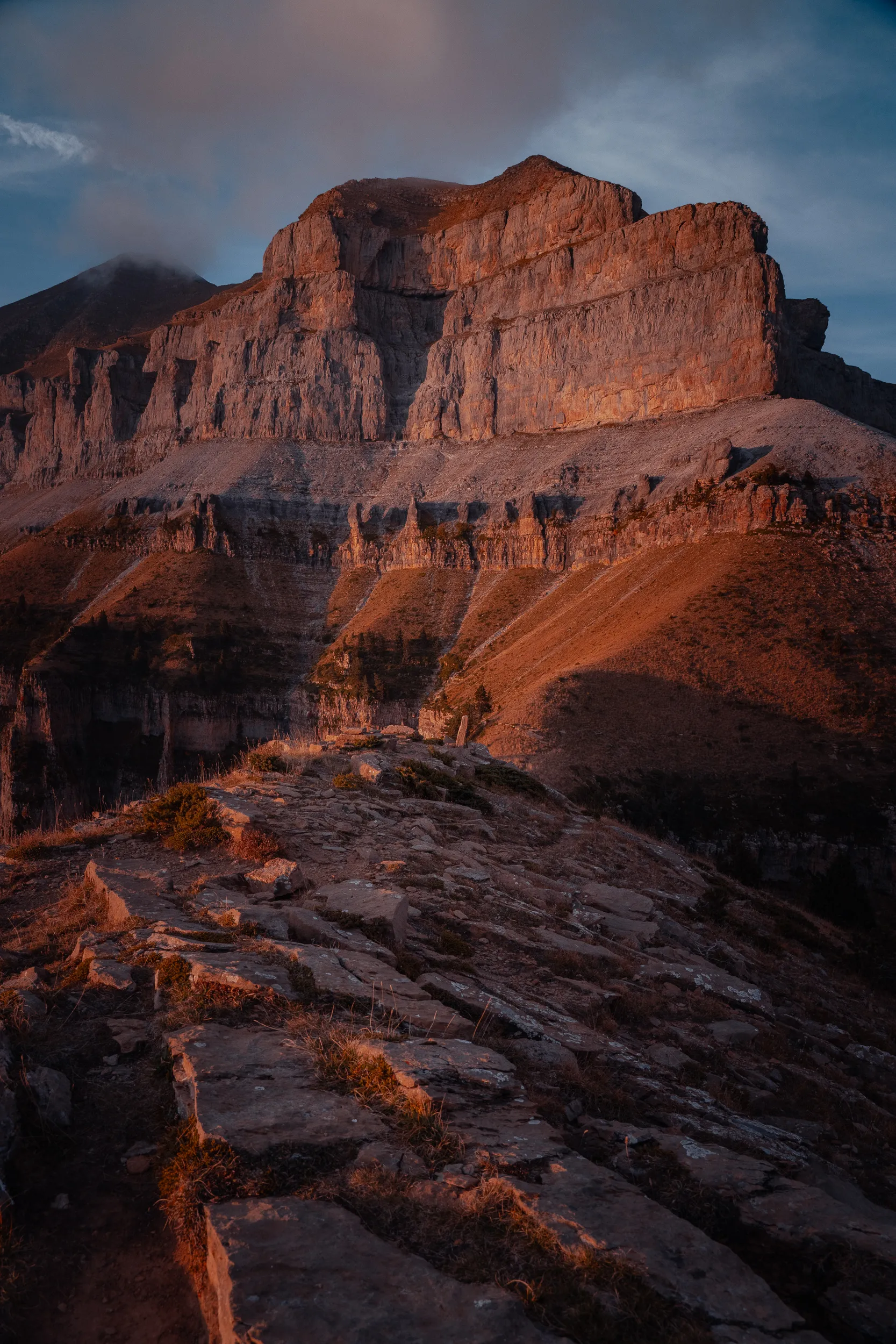 Une immense muraille calcaire d'Ordesa éclairée par le soleil couchant, au-dessus de dalles rocheuses