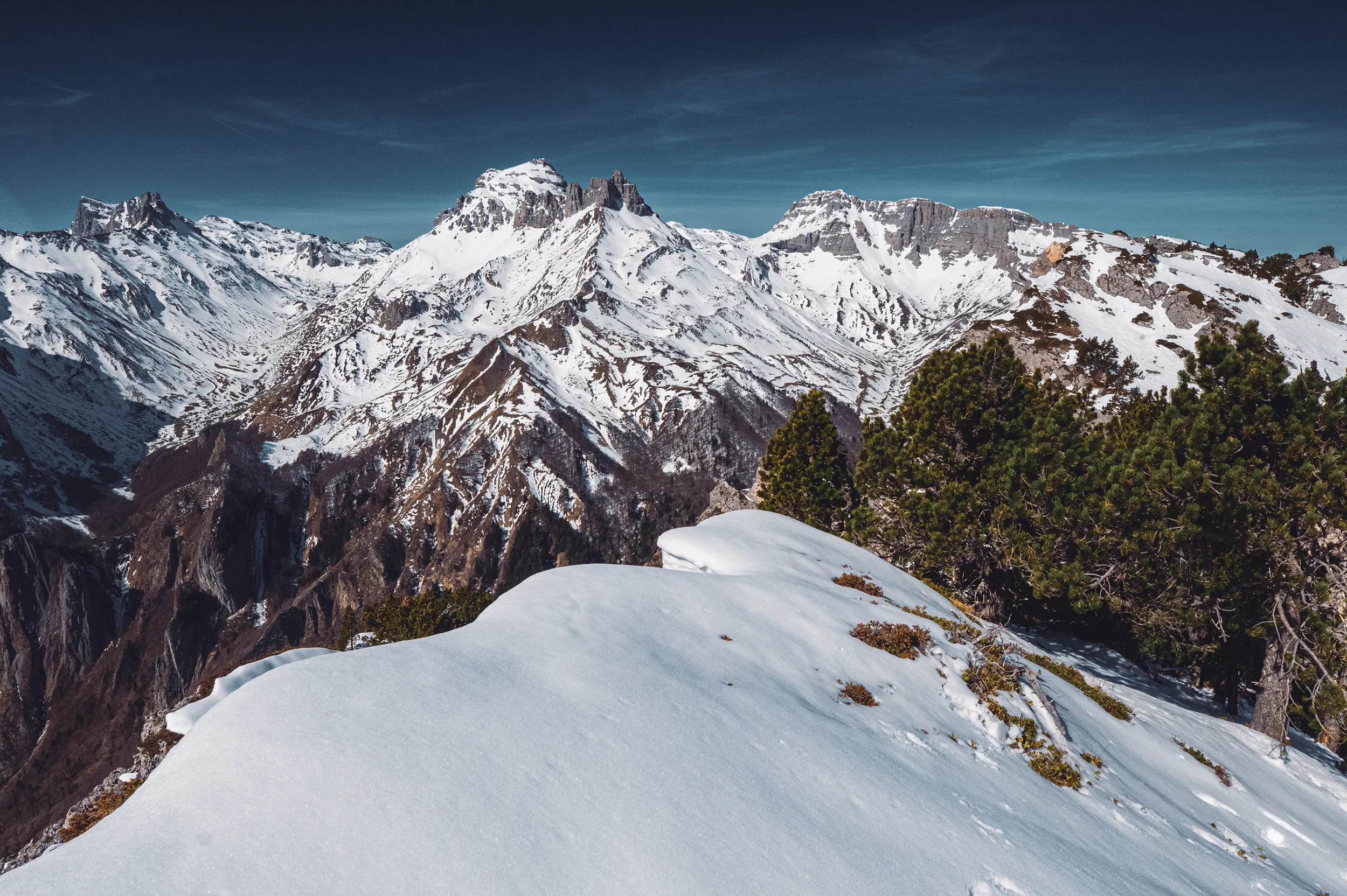Panorama de sommets enneigés du Béarn sous un ciel bleu, depuis une crête de neige près des orgues de Camplong