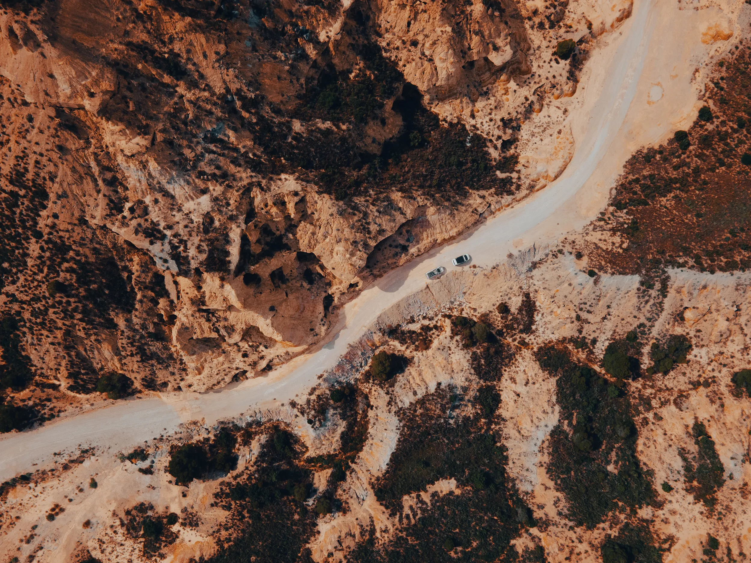 Vue aérienne au drone de 4x4 sur une piste serpentant entre les ravines ocre du désert des Monegros