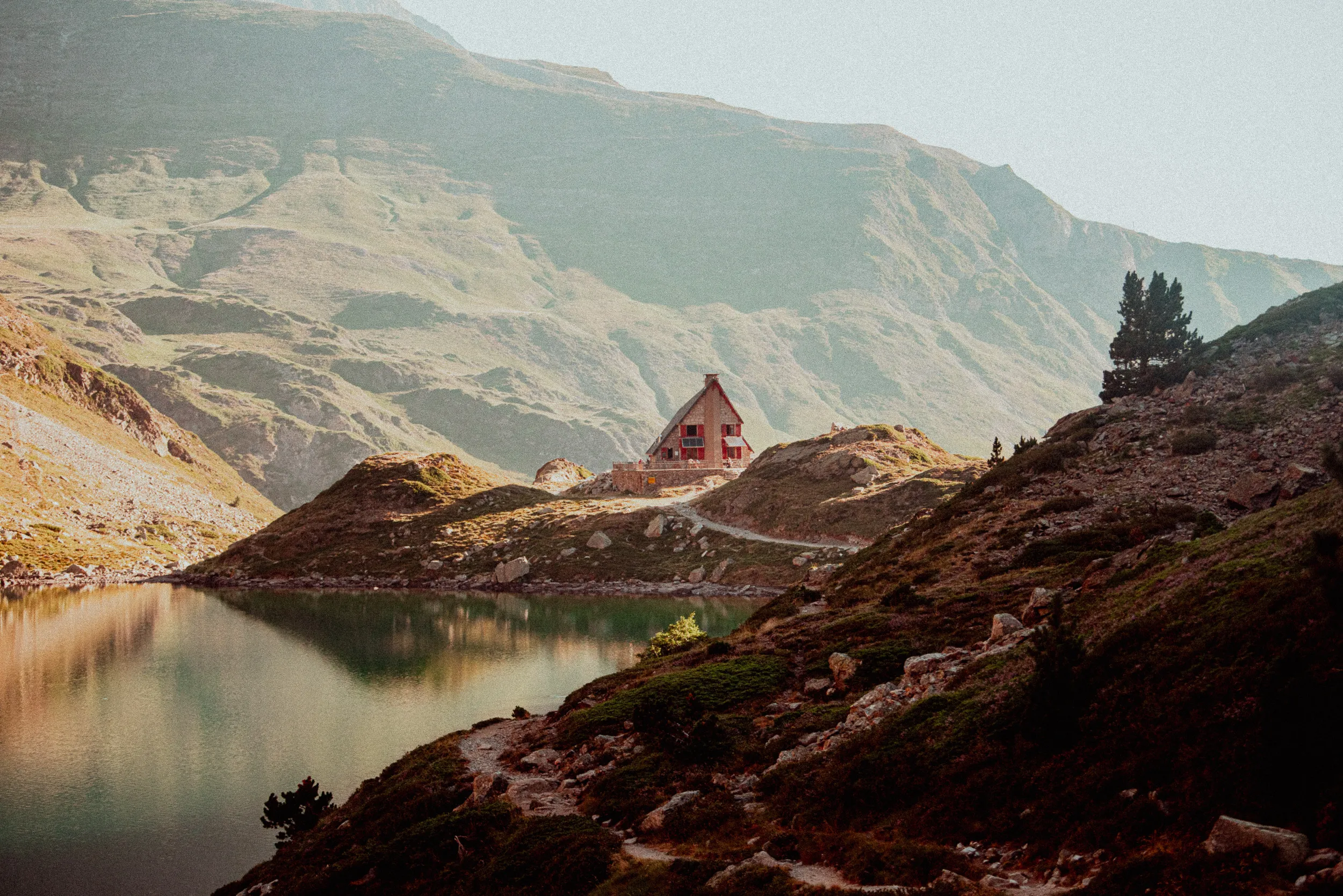 Le refuge d'Ilhéou au bord du lac Bleu d'Ilhéou, baigné de lumière chaude, au-dessus de Cauterets