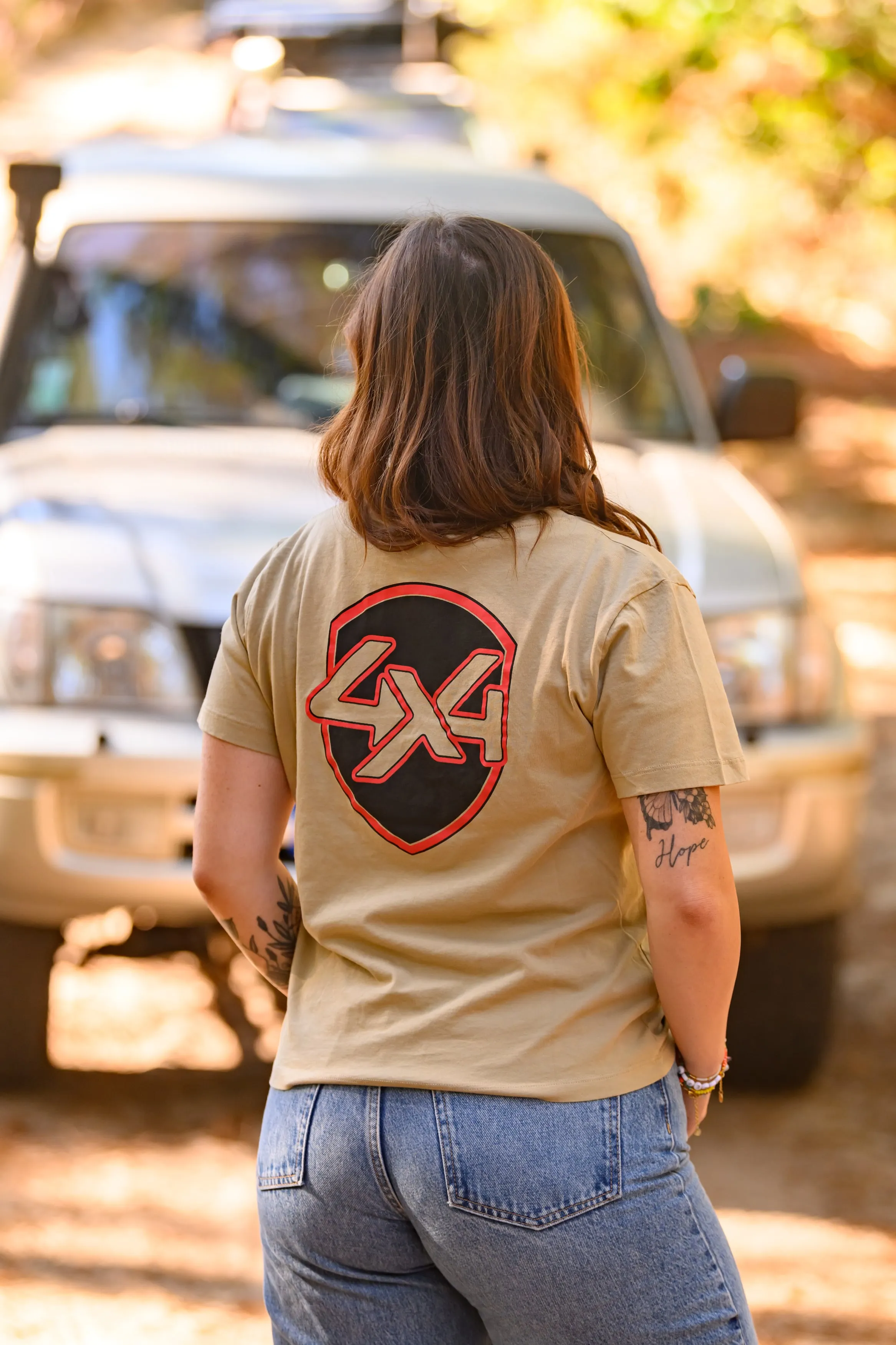 Tee-shirt au logo 4x4 vu de dos, devant un 4x4 dans la lumière du soir
