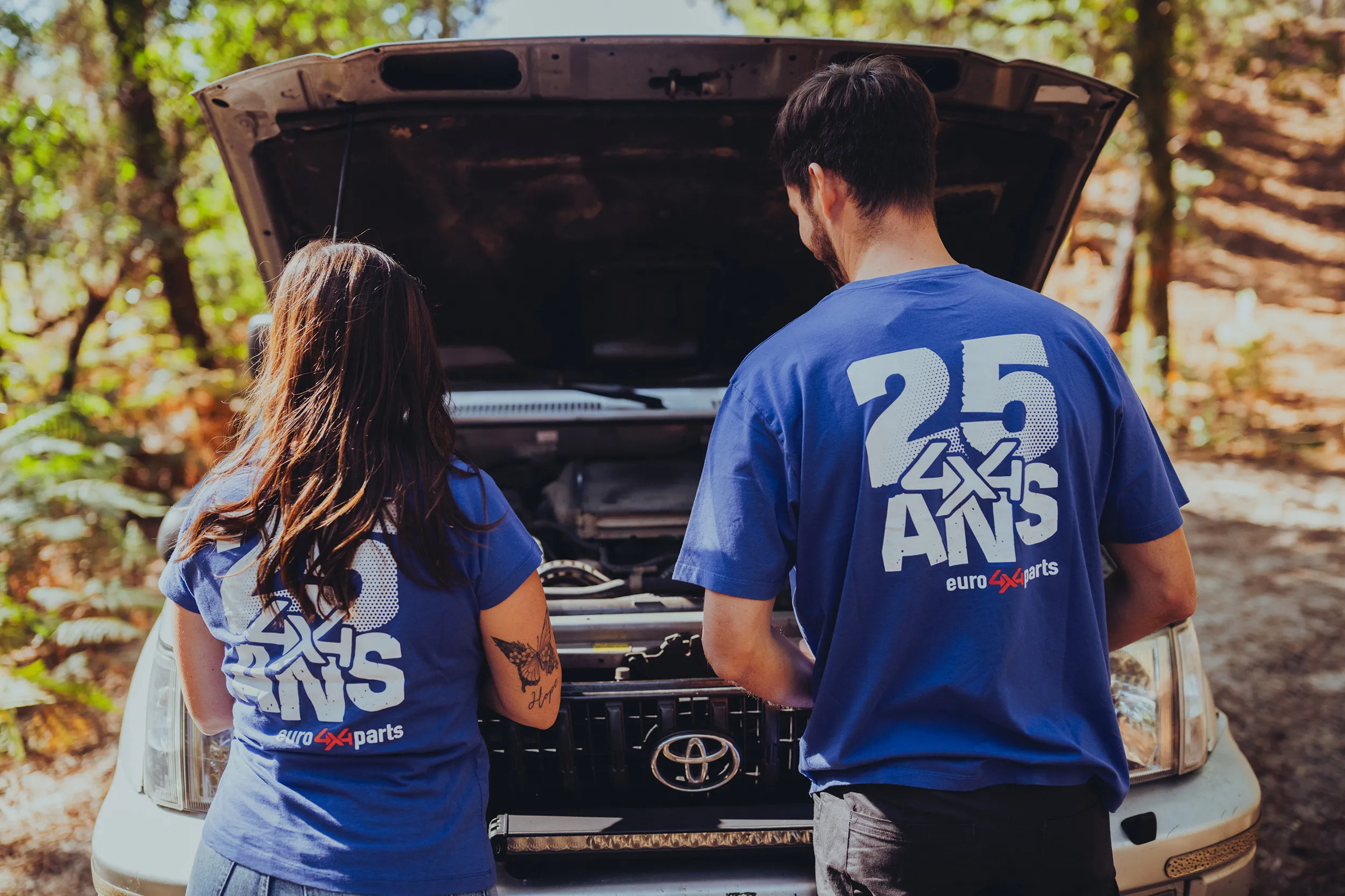 Couple en tee-shirts des 25 ans d'Euro4x4Parts devant un capot ouvert
