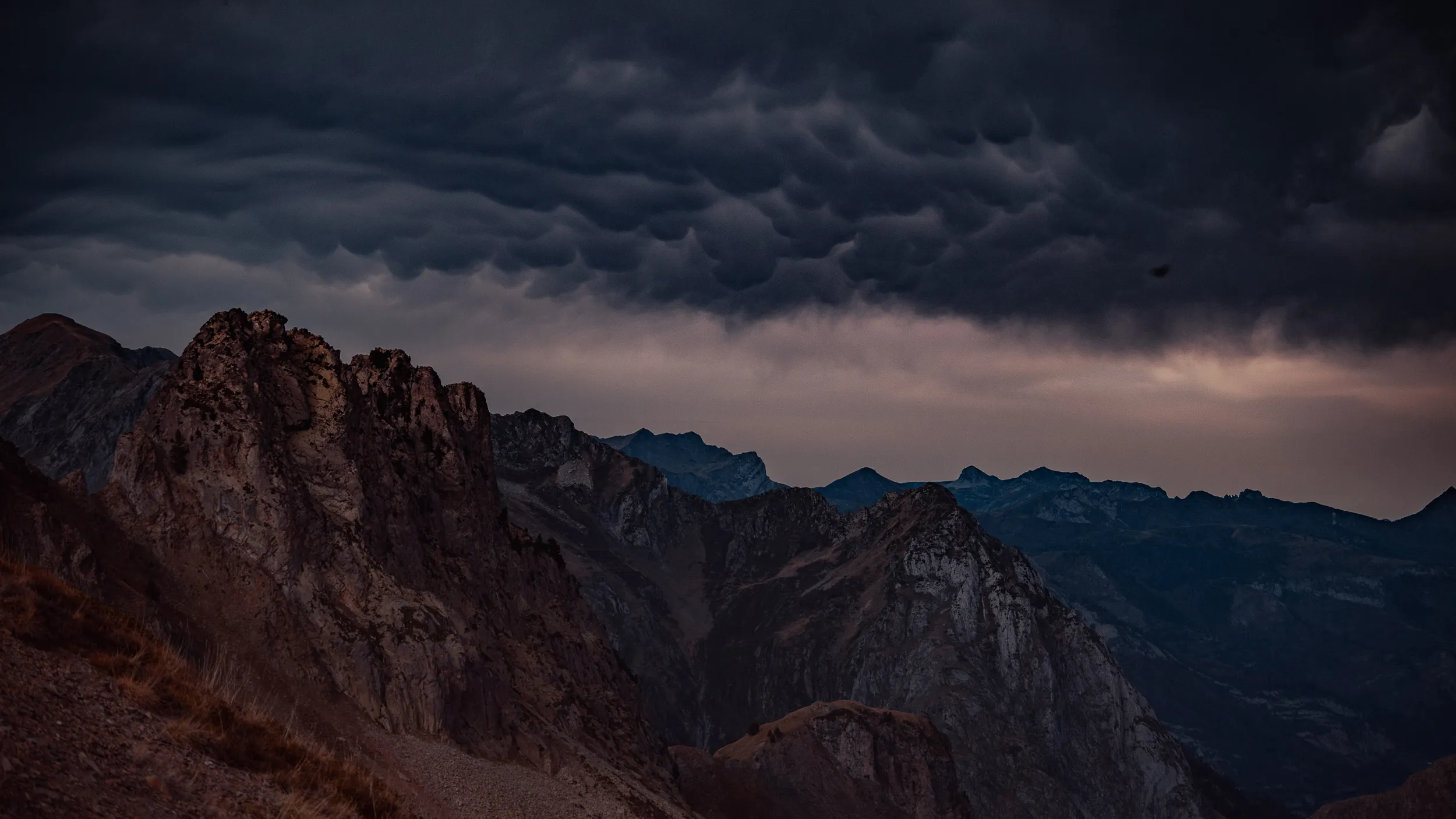 Panorama de crêtes rocheuses sous un ciel d'orage chargé de mammatus, vallée d'Ossau