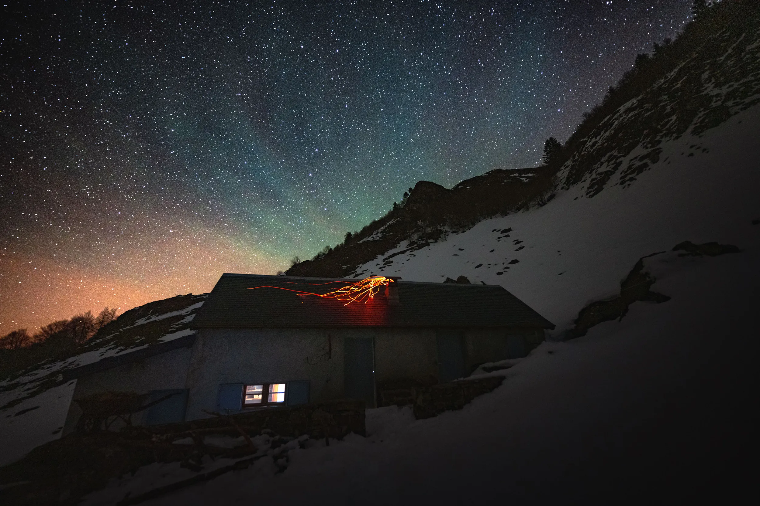 Une cabane pastorale éclairée sous un ciel étoilé, sur une pente enneigée du vallon de Belonce