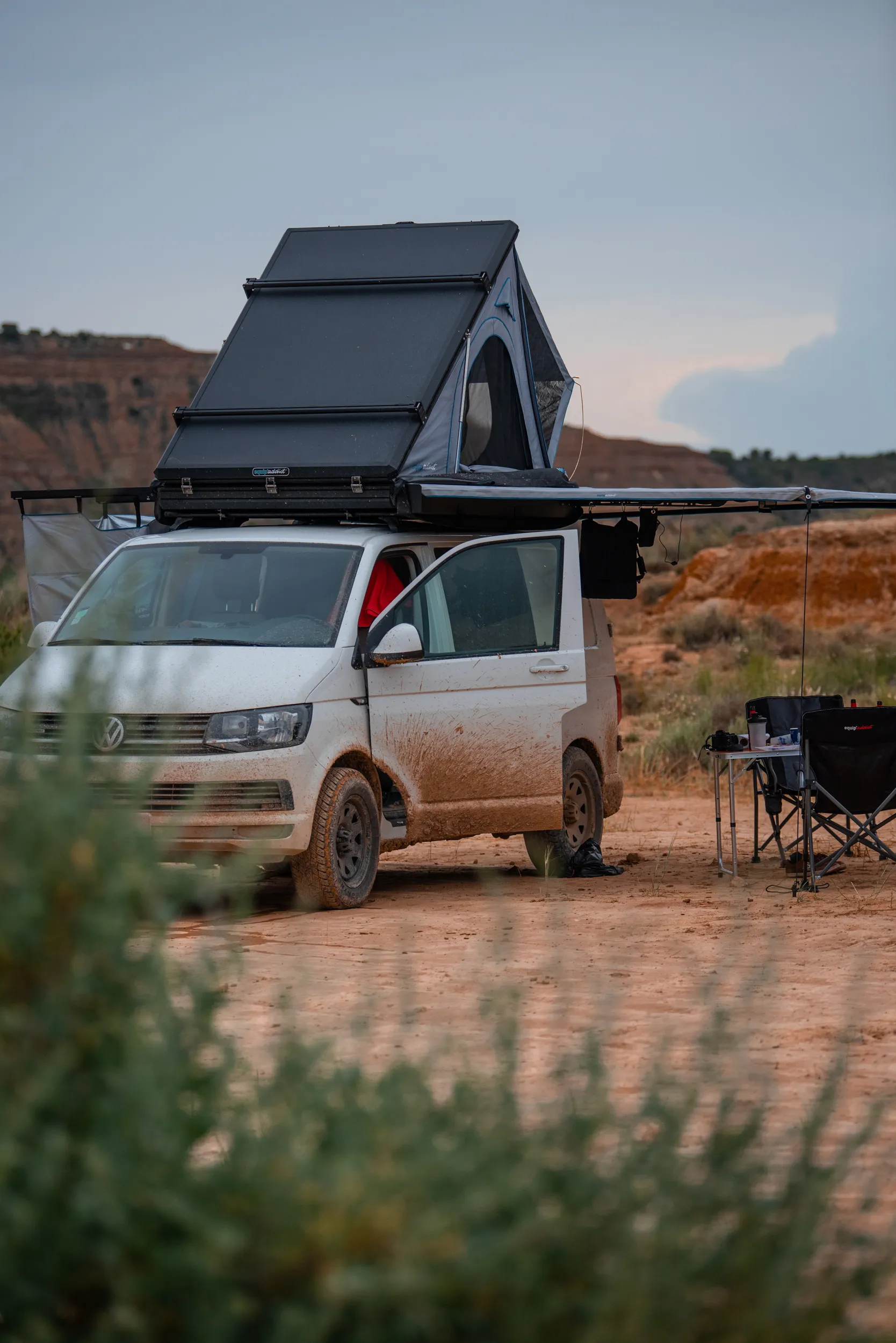 Van équipé d'une tente de toit et d'un auvent, au bivouac dans un paysage désertique