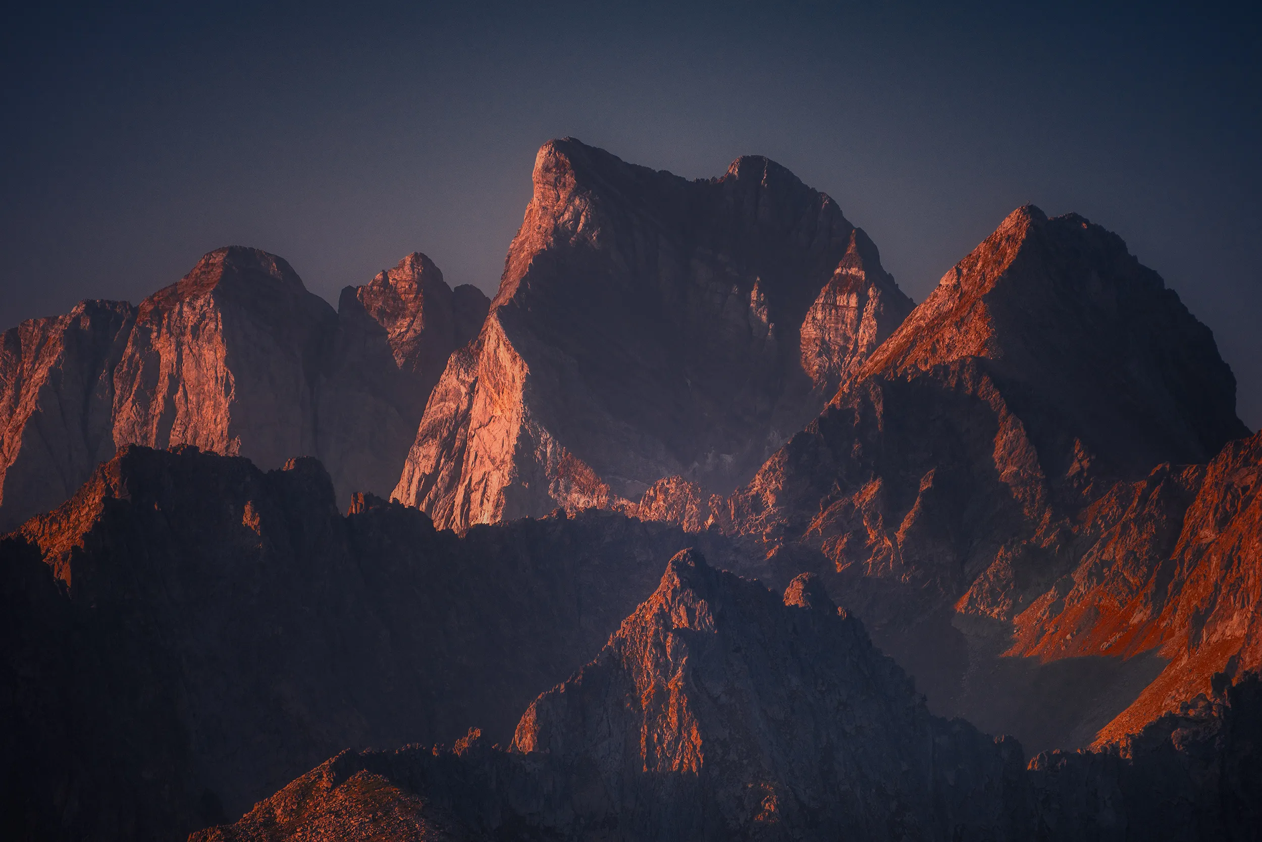 Les arêtes déchiquetées du massif du Vignemale rougies par la dernière lumière du jour